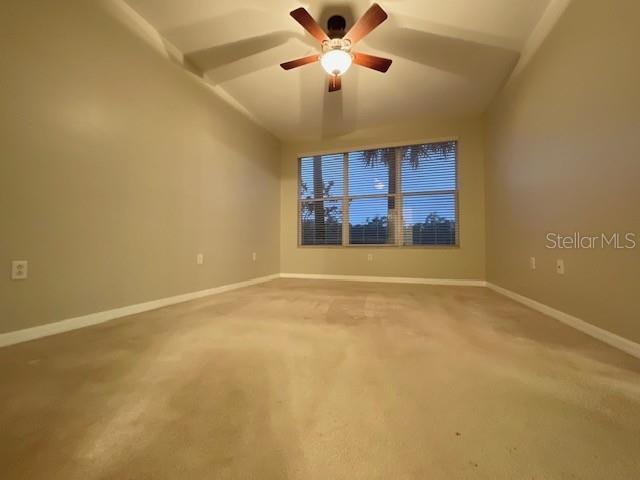 carpeted spare room with lofted ceiling and ceiling fan