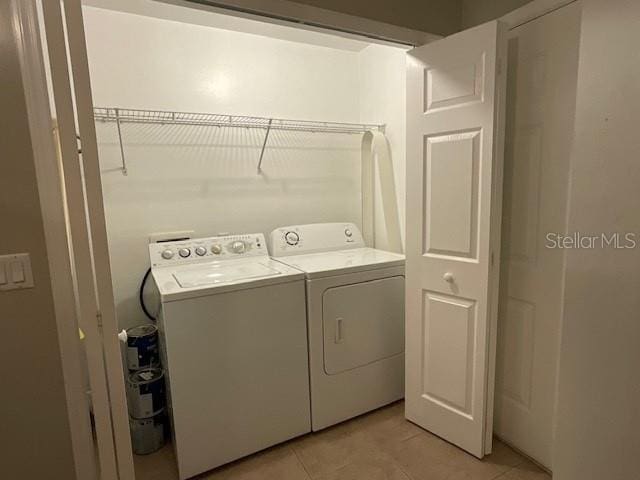 clothes washing area featuring light tile patterned flooring and washer and dryer