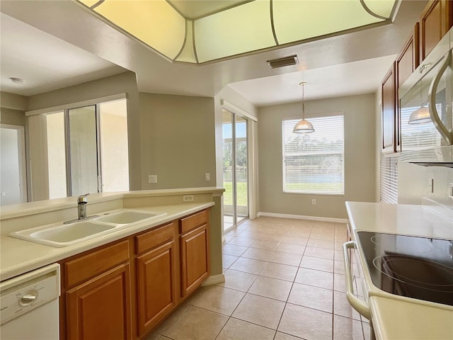 kitchen featuring hanging light fixtures, sink, light tile patterned floors, and white appliances