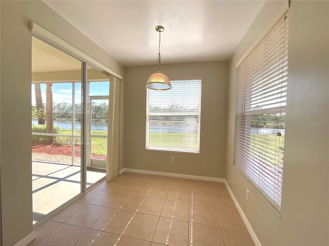 unfurnished dining area with a water view and tile patterned floors