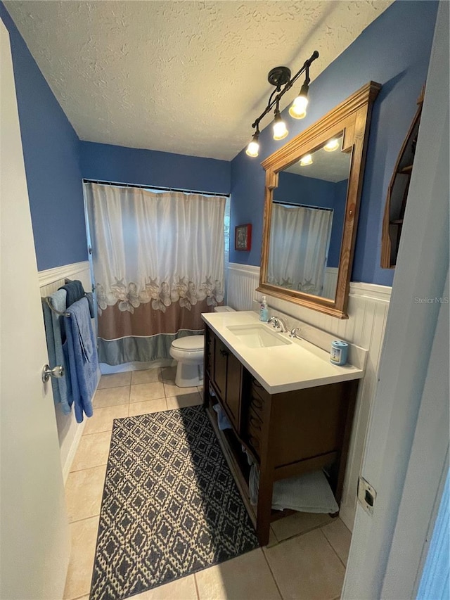 bathroom with tile patterned floors, vanity, toilet, and a textured ceiling