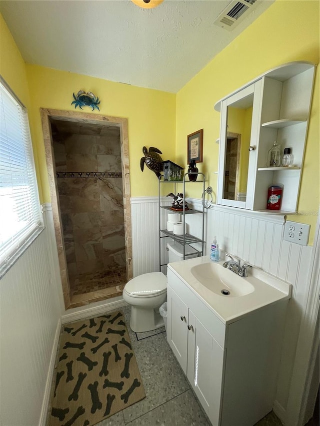 bathroom featuring vanity, toilet, tile patterned flooring, and a tile shower