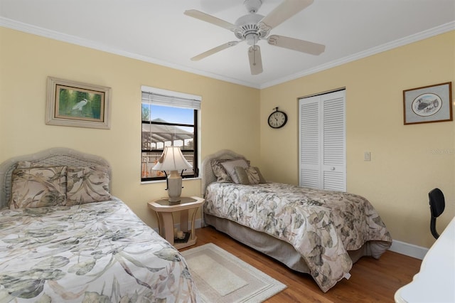 bedroom with crown molding, ceiling fan, wood-type flooring, and a closet