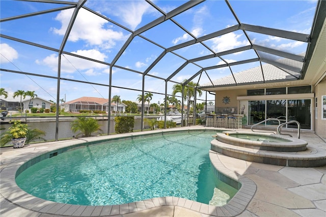 view of swimming pool with exterior bar, an in ground hot tub, glass enclosure, a water view, and a patio area