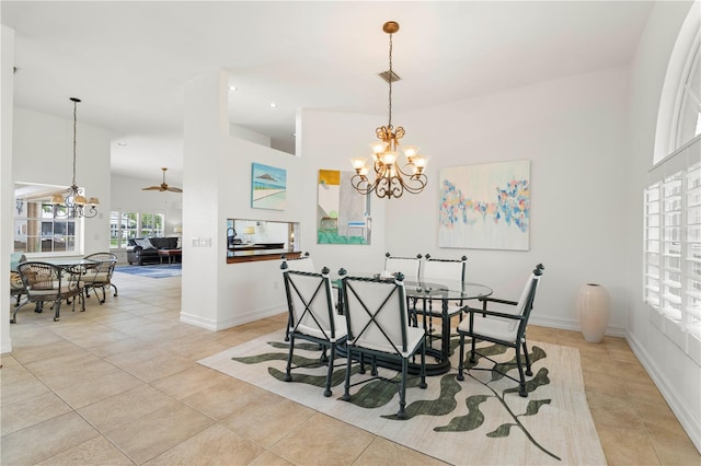 tiled dining space with a high ceiling and ceiling fan with notable chandelier