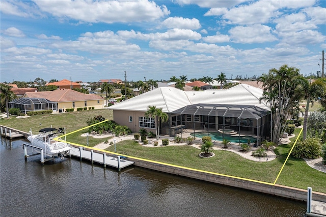 rear view of house with a water view, glass enclosure, and a lawn