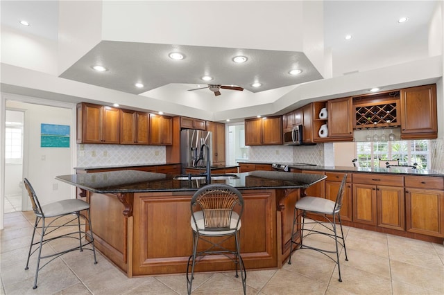 kitchen featuring appliances with stainless steel finishes, dark stone countertops, a kitchen bar, and a spacious island