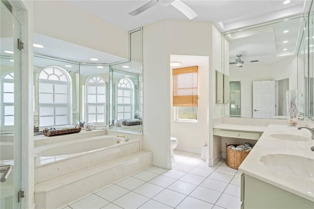 bathroom with tile patterned floors, toilet, vanity, ceiling fan, and tiled bath