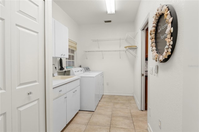 washroom featuring sink, washing machine and dryer, cabinets, and light tile patterned flooring