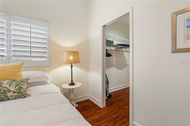 bedroom with dark hardwood / wood-style flooring, a spacious closet, and a closet