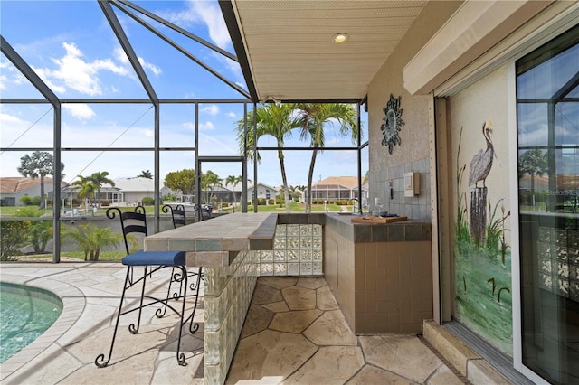 view of patio with a pool, an outdoor bar, and glass enclosure