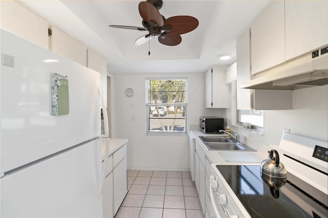 kitchen featuring sink, light tile patterned floors, white cabinets, a raised ceiling, and white fridge