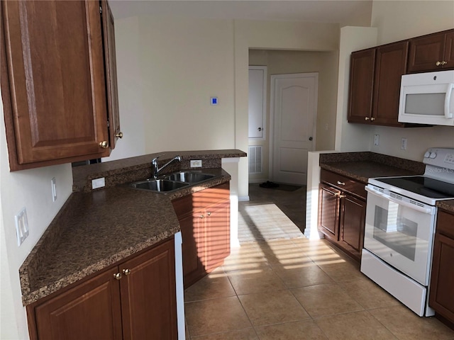 kitchen with light tile patterned flooring, white appliances, sink, and dark stone countertops