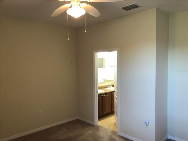 carpeted empty room featuring ceiling fan and sink