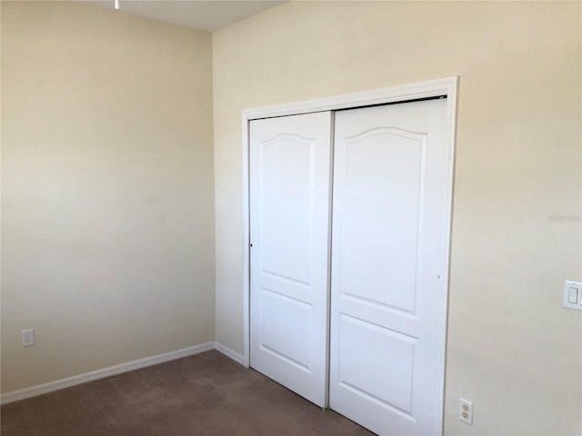 unfurnished bedroom with a closet and dark colored carpet