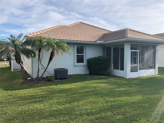 back of property featuring central AC, a sunroom, and a lawn