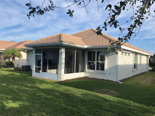 back of property with a sunroom, a yard, and central AC