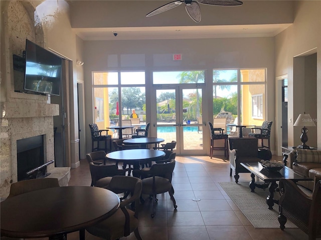 dining space featuring french doors, a large fireplace, tile patterned floors, and a towering ceiling