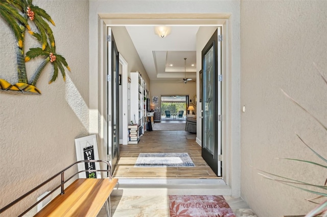 doorway to property with hardwood / wood-style flooring and a tray ceiling