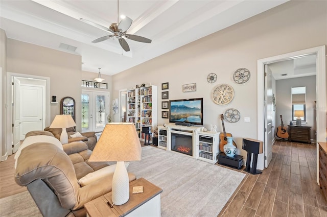 living room featuring a raised ceiling, ceiling fan, dark hardwood / wood-style flooring, and french doors