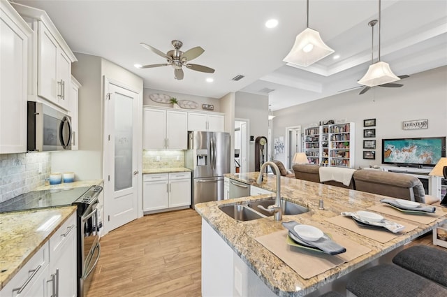 kitchen featuring sink, stainless steel appliances, white cabinets, and a center island with sink