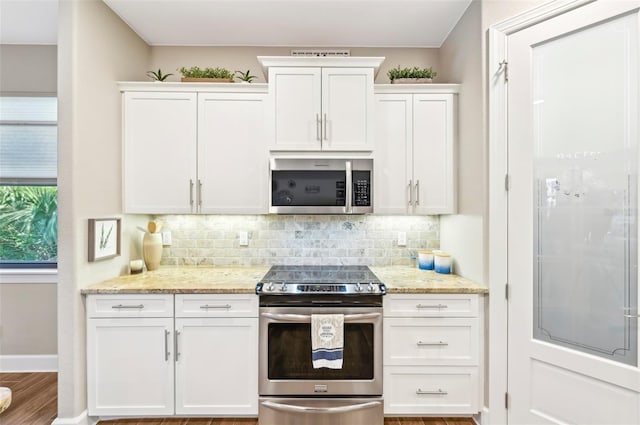 kitchen featuring hardwood / wood-style floors, tasteful backsplash, white cabinetry, stainless steel appliances, and light stone countertops