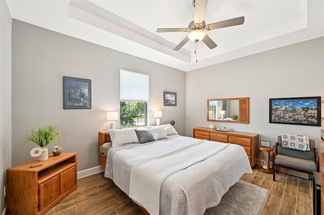 bedroom with ceiling fan and a tray ceiling