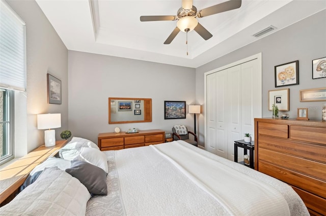 bedroom featuring a closet, ceiling fan, and a tray ceiling