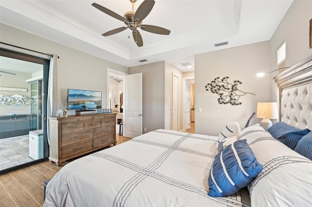 bedroom with ornamental molding, connected bathroom, ceiling fan, and a tray ceiling