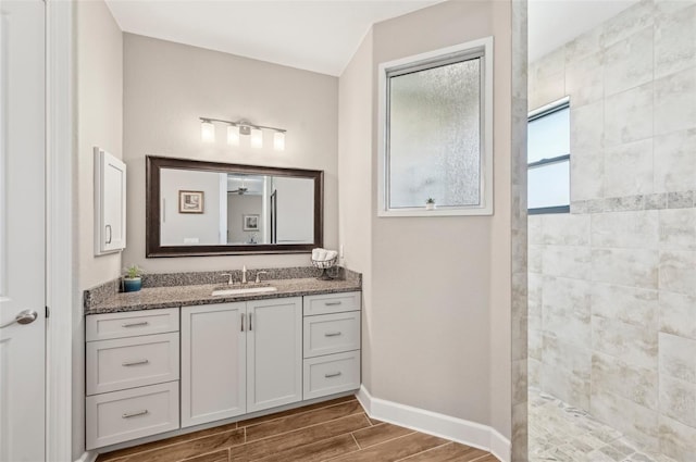 bathroom with tiled shower and vanity