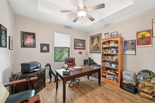 office with a tray ceiling, light hardwood / wood-style floors, and ceiling fan