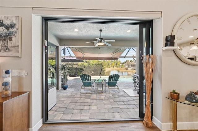 doorway featuring a textured ceiling and ceiling fan