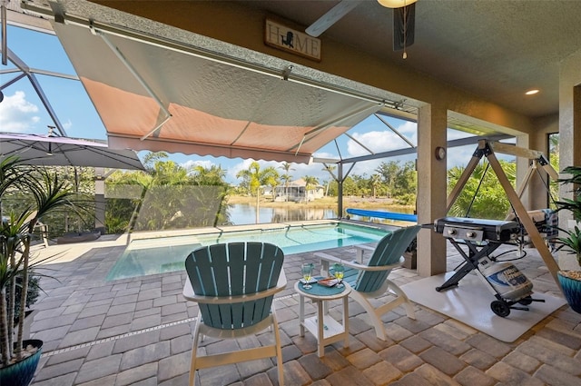 view of patio / terrace with a water view, ceiling fan, and a lanai