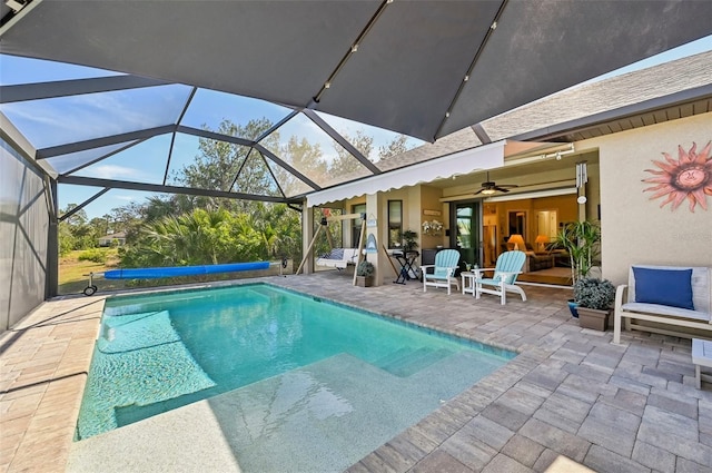 view of swimming pool with ceiling fan, a patio, and glass enclosure