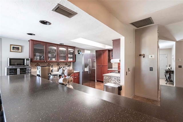 kitchen with stainless steel appliances, kitchen peninsula, and decorative backsplash