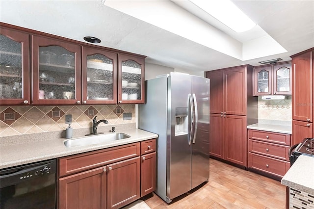 kitchen with sink, decorative backsplash, black appliances, and light wood-type flooring