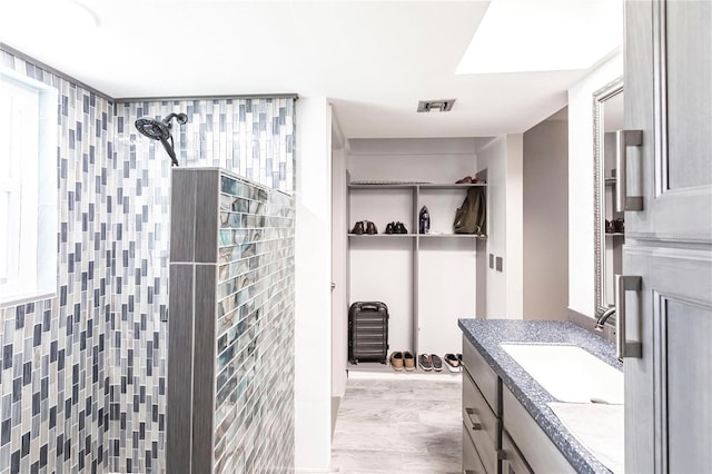 bathroom with hardwood / wood-style flooring, vanity, and a shower