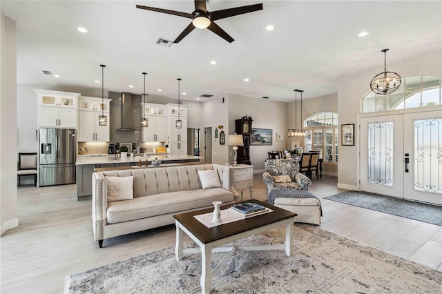 living room with french doors, ceiling fan with notable chandelier, and light hardwood / wood-style flooring