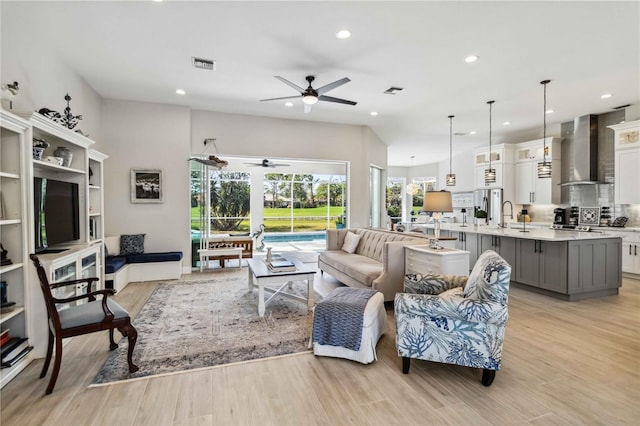 living room with ceiling fan, sink, and light hardwood / wood-style flooring