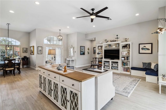 kitchen featuring ceiling fan with notable chandelier, pendant lighting, wood counters, white cabinets, and light wood-type flooring