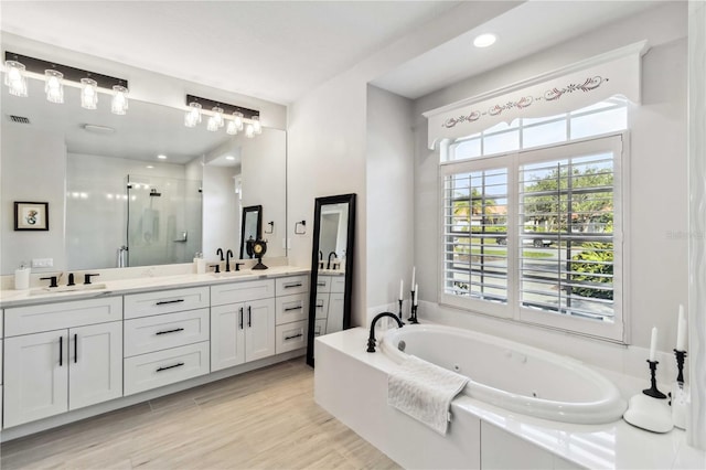 bathroom featuring hardwood / wood-style flooring, vanity, and plus walk in shower