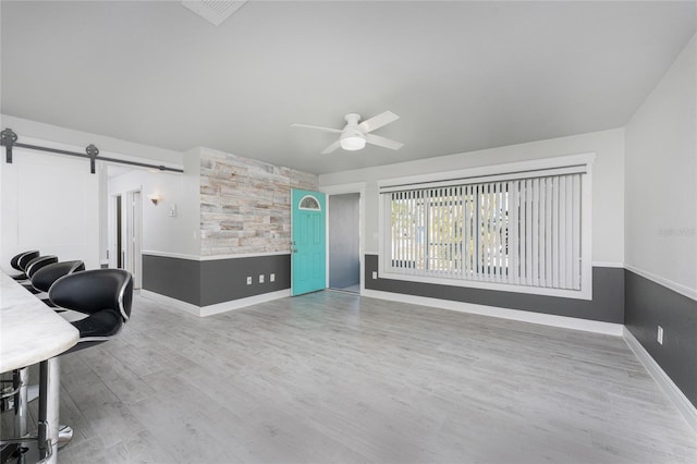 interior space featuring wood-type flooring, a barn door, and ceiling fan