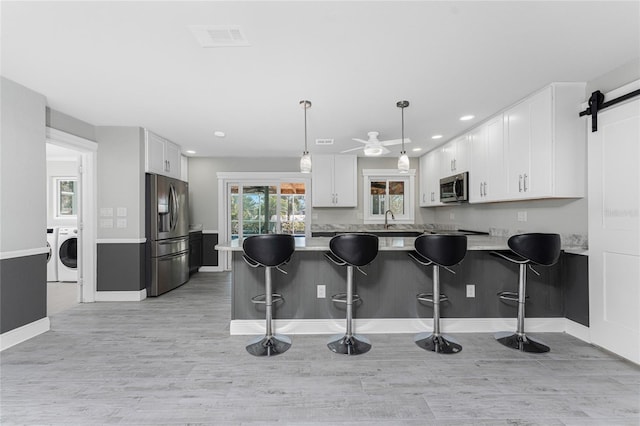 kitchen featuring pendant lighting, kitchen peninsula, white cabinets, and appliances with stainless steel finishes