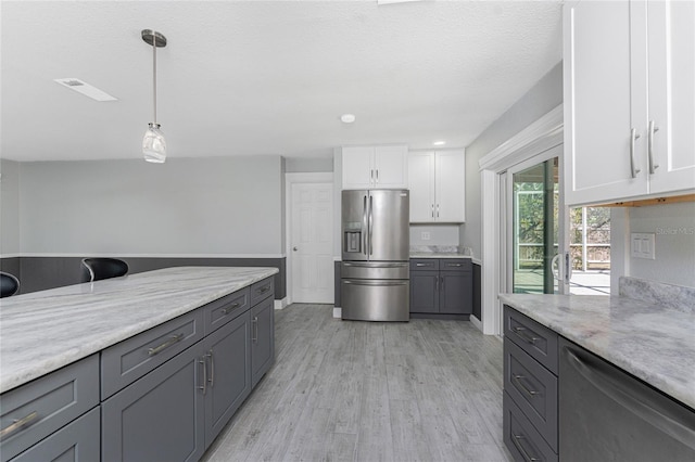 kitchen with white cabinetry, appliances with stainless steel finishes, light stone countertops, and hanging light fixtures