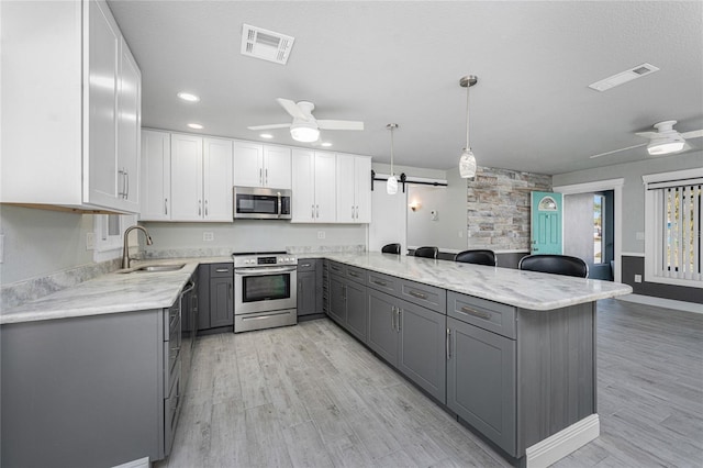 kitchen with decorative light fixtures, gray cabinets, stainless steel appliances, and white cabinets