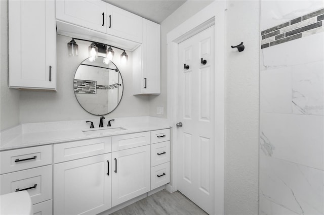 bathroom with vanity, hardwood / wood-style floors, and tiled shower