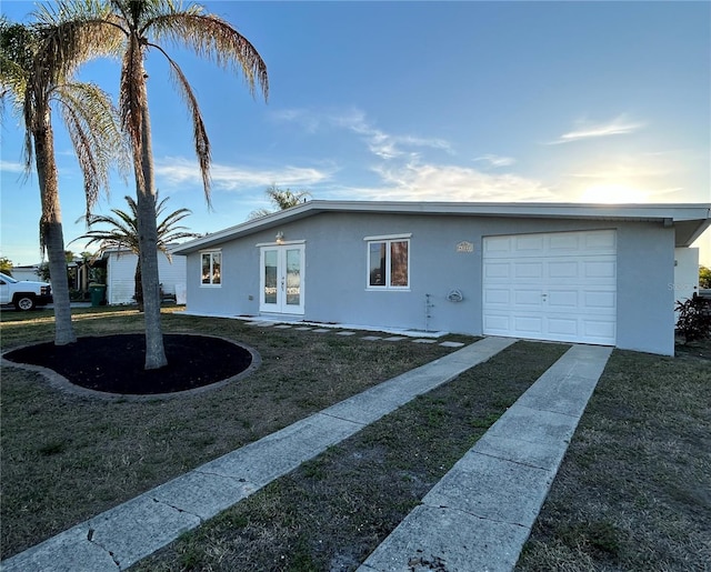 ranch-style house featuring french doors, a garage, and a front yard