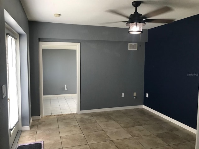 empty room featuring a healthy amount of sunlight, light tile patterned floors, and ceiling fan