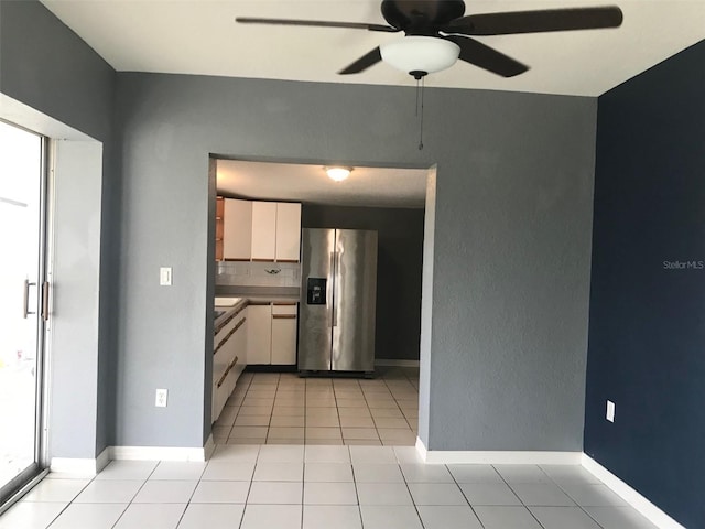 kitchen with stainless steel refrigerator with ice dispenser, light tile patterned floors, ceiling fan, decorative backsplash, and white cabinets