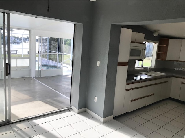 kitchen featuring black electric cooktop, white cabinets, sink, and light tile patterned floors